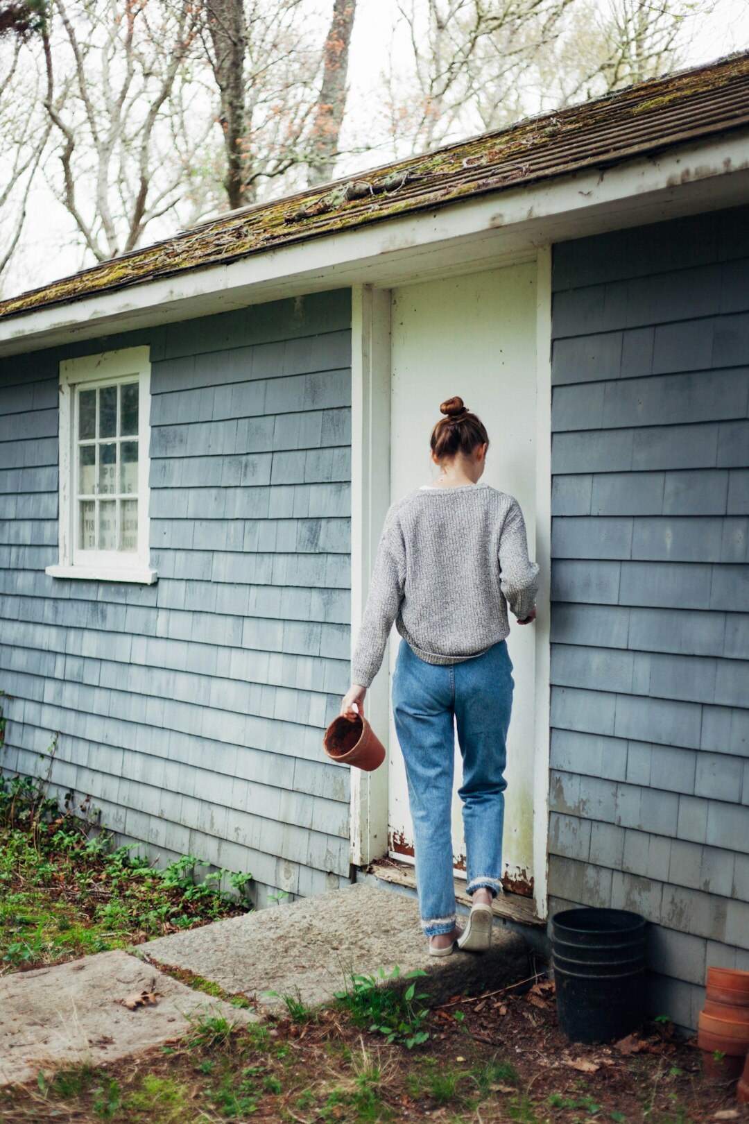 Czech woman kneeling and planting flowers in a flower bed near a countryside cottage